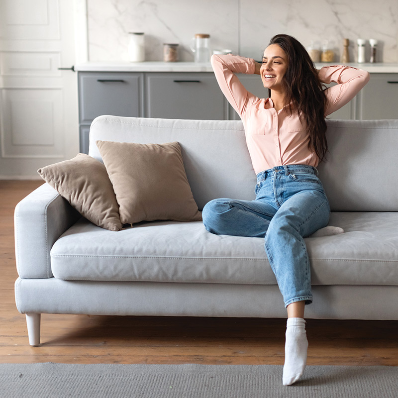 Relaxed woman on couch with her hands behind her head.